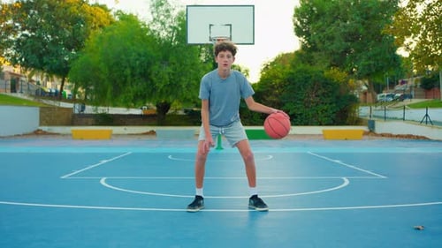 Teen Boy Dribbling Basketball on an Outdoor Court