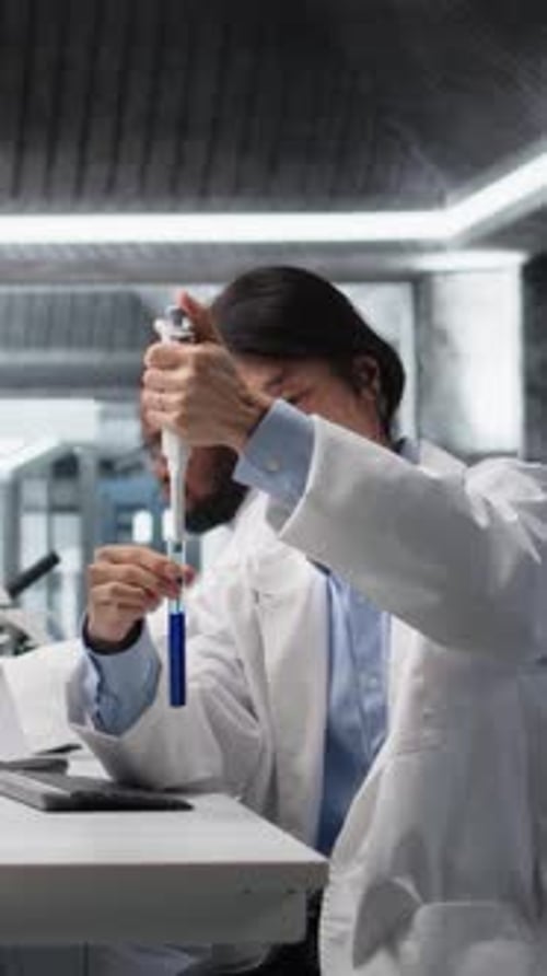 Scientist Pipetting Blue Liquid into Test Tube