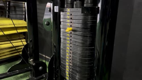 Detail eines Mannes, der Gewichtsveränderungen an Fitnessgeräten vornimmt.