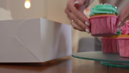 Hand Placing Decorative Cupcake into White Box