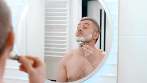 Face in mirror and shaving cream, hygiene and grooming with beauty and skincare in morning