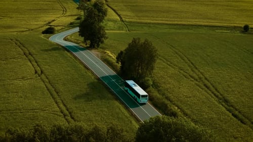 Transport fährt bei Sonnenuntergang durch kurvige Straße auf offenen Feldern Weißer Bus fährt durch die Landschaft