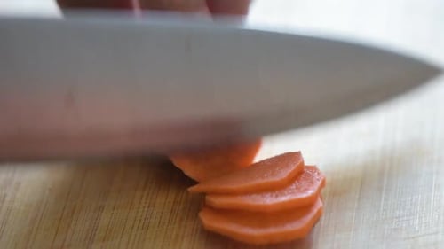 Close-up of Woman's hand cutting a carrot.Side frame.