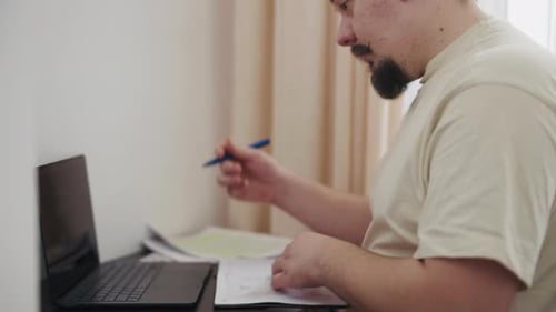 Man at Desk Working with Computer and Paperwork