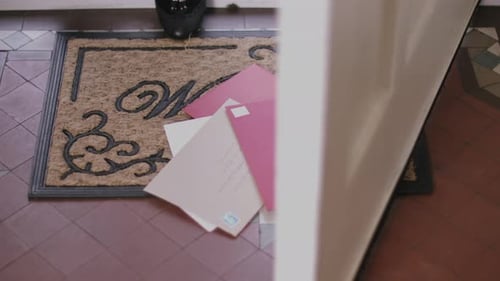 Woman picking up letters from doormat