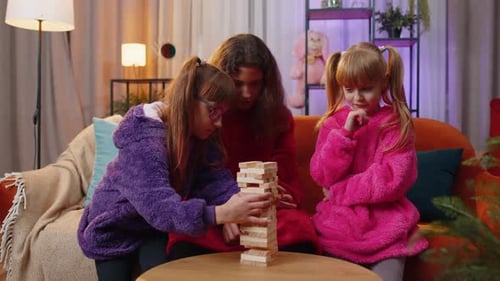 Three Siblings Children Girls Playing with Blocks Board Game Build Tower From Wooden Bricks at Home