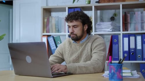 Man Typing on Laptop in Office