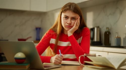 Woman Looks Bored While Studying in Kitchen