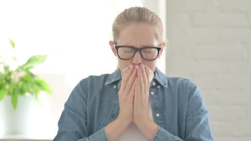 Young Woman Sneezing into Tissue indoors