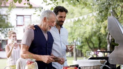 Family enjoys garden party with father and son barbecuing in the sunshine