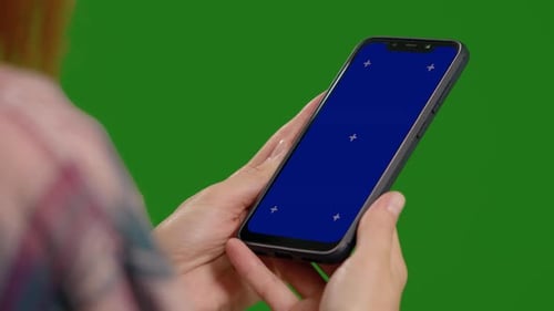 Female watching attentively blue chroma key screen on vertical smartphone.