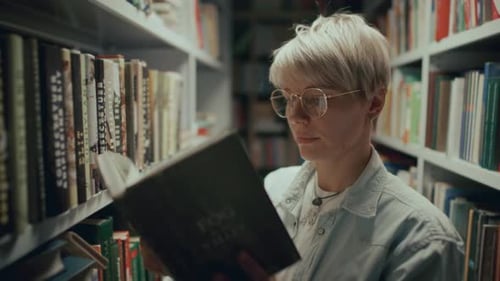 Jovem mulher lendo livro entre prateleiras durante visita à biblioteca