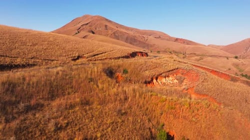Aerial Views Capture a Winding Road Cutting Through a Sunlit Mountain Range in Madagascar