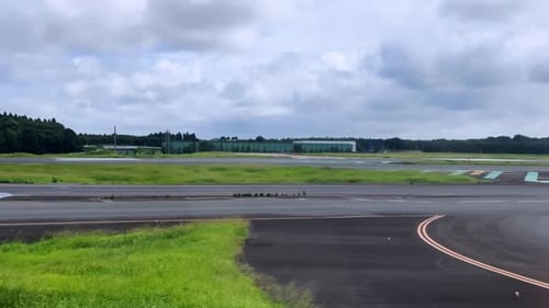 Blick aus einem Flugzeug auf die Landebahn, bereit für den Start an einem bewölkten Tag mit grünen Feldern in der Nähe