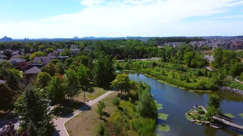 Aerial view of houses in neighborhood and park. Flying forward and pushing higher to reveal the cit