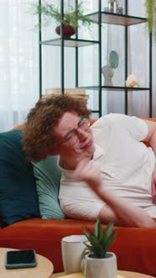 Young Man Experiencing Stomach Pain on Orange Sofa