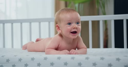 Joyful Infant Lying in Crib Looking Off-Camera