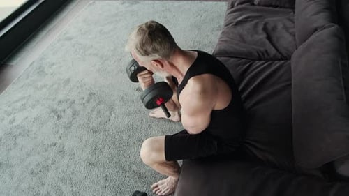 Mature Man Exercising Biceps with Dumbbell in Living Room