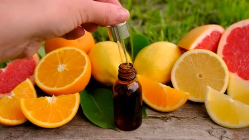 Dropper Dispensing Oil Surrounded By Citrus Fruits