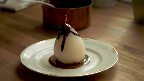Chef Pouring Rich Chocolate Sauce Over a Gourmet Poached Pear