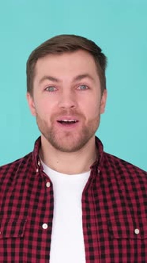 Portrait of a Handsome Smiling Young Man Looking Surprised at the Camera in a Colorful Studio
