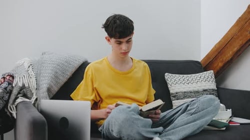 Young Person Reading a Book While Sitting Comfortably on a Couch in a Cozy Living Room with