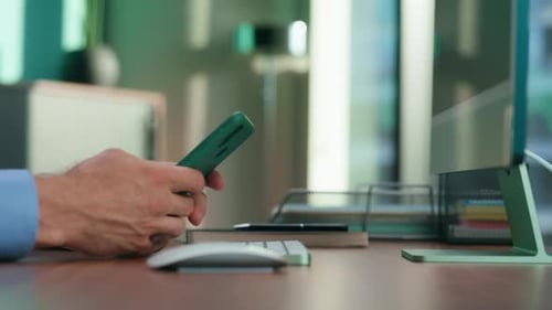 Man at Desk Using Phone and Typing