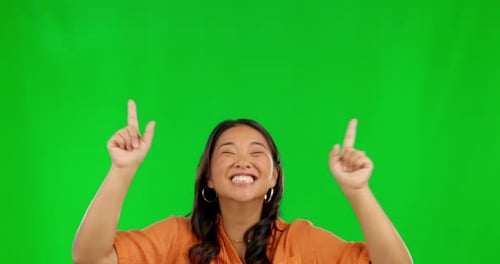 Excited asian woman, pointing and advertising on green screen against studio background