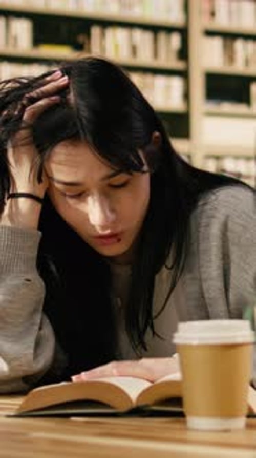 Vertical Video Exhausted Young Woman Reading Open Book at University Library Desk