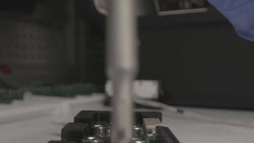 Employee Twists Screw on Detail of Refrigerator at Workplace