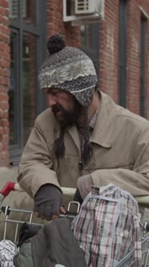 Vertical of Bearded Homeless Man Walking down Street Searching for Bottles