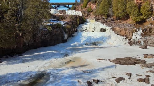 Rocky river in the middle of a snowy forest. Aerial view of Gooseberry Falls, Minnesota.