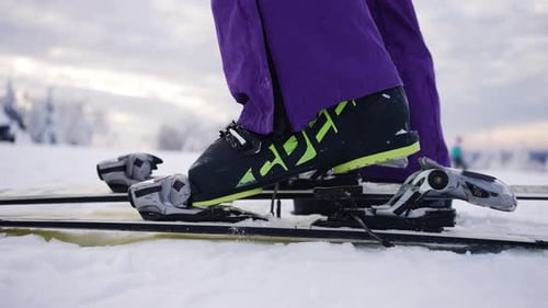 Skier Fastening and Unfastening Ski Boots Bindings on Mountain Top