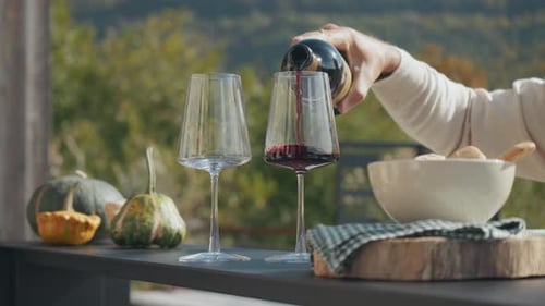 A Relaxing Moment Pouring Red Wine into a Glass in the Outdoor Kitchen