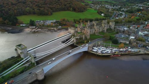 Drone view of car traffic on suspension bridge and Conwy Castle, North Wales in UK. Aerial sideways