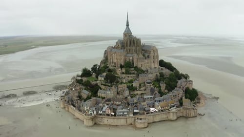 mont saint michel drone camera taking cinematics shot from top angle, lots of gardens next to buildi