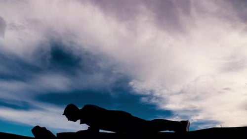 Silhouette puissante d'un homme en forme faisant des pompes sur un ciel Thétral. Il fait face à la gauche et