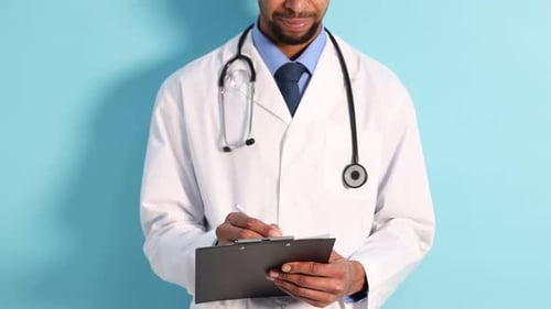 Serious Male Doctor Writing on Clipboard in Studio