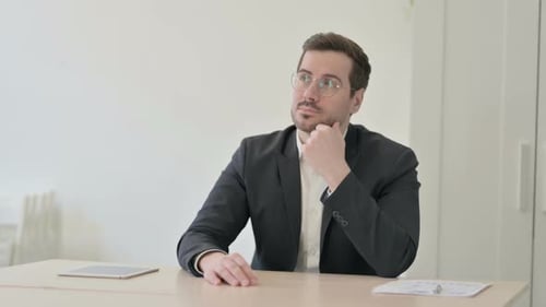Man in Suit Thinking at Desk in Office