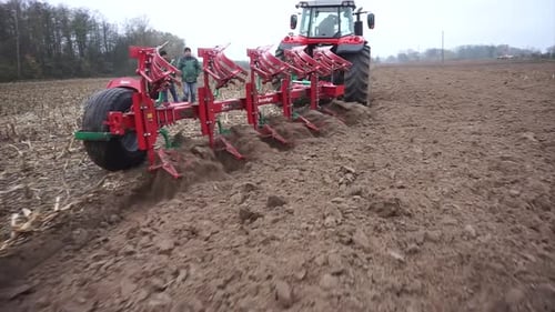Red tractor plowing the field in Ukraine