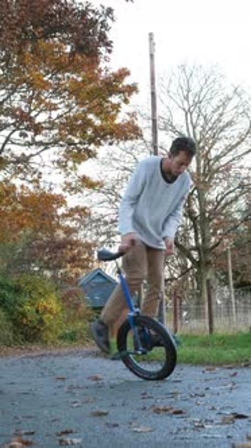 Rider showing impressive stunts and tricks while riding a unicycle in an autumn park