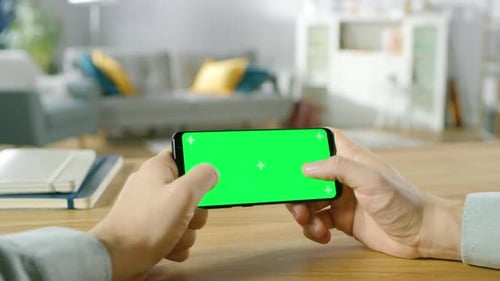First Person Close-up of the Man Holding Green Screen Smartphone in Landscape Mode and Playing Game