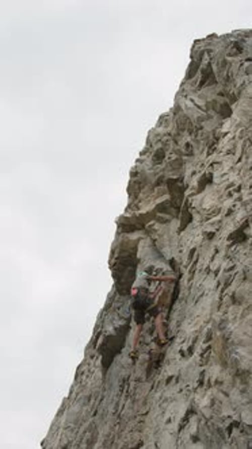 Alpinist Climbing Rocky Cliff on Summer Day