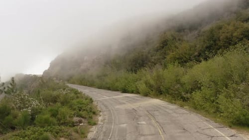 Drone flying forward over an asphalt mountain road. Aerial view of a mountain road in San Gabriel Mo