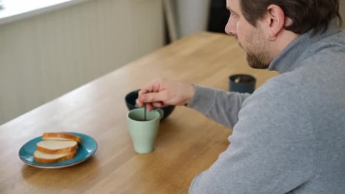 Handsome Man Eating Granola Bar in Kitchen Drinking Tea Healthy Food Health Care Nutrition Male