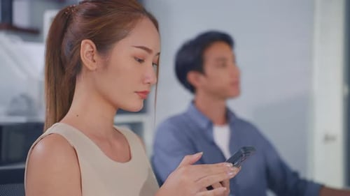 Asian happy businesswoman talking on smartphone and working in office.