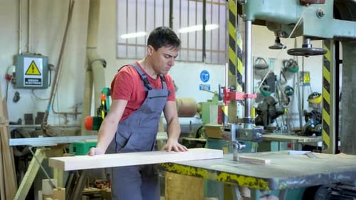 Carpenter Cutting Wood with Band Saw in Workshop