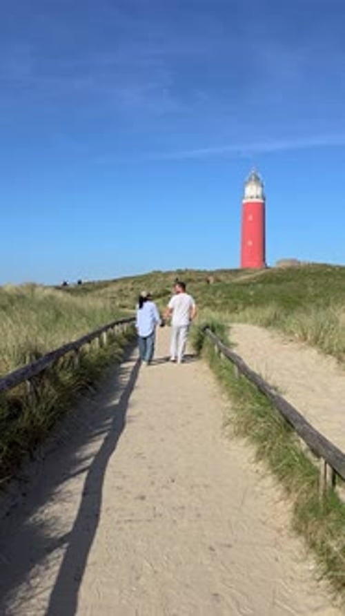A Diverse Couple of Men and Women Walking on a Path to the Lighthouse of Texel Netherlands