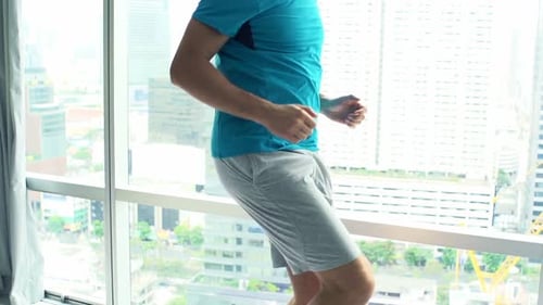 Jeune homme faisant un échauffement, courant par la fenêtre chez Luxury Home Active