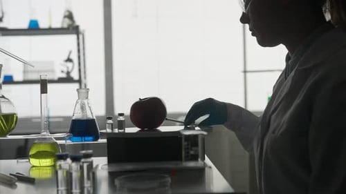 Dark Silhouette of a Female Scientist with a Syringe in a Laboratory The Woman Injects Liquid Into a